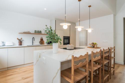 a kitchen with white cabinets and a white island with chairs at Maison la Bruyere, 4 bedroom villa - pool, airco & hottub in Franschhoek