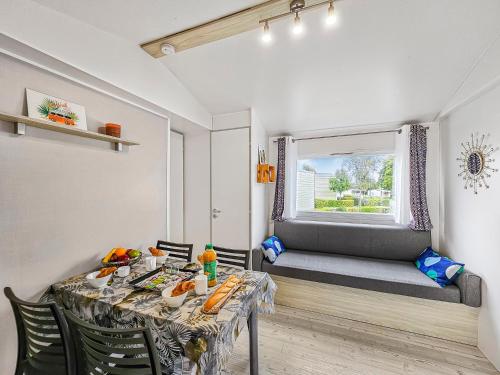 una sala da pranzo con tavolo, sedie e una finestra di L'Esprit Vintage, terrasse couverte a Litteau
