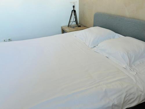 un lit blanc avec des draps et des oreillers blancs dans l'établissement Très bel appartement Nice vue mer, à Nice