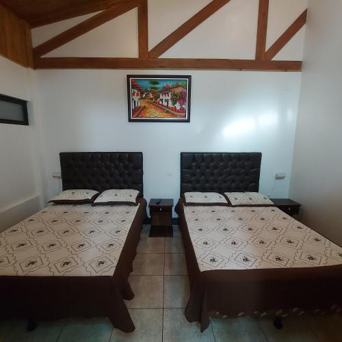 two beds in a room with wooden ceilings at Alisson Hotel y Restaurant in Monteverde Costa Rica