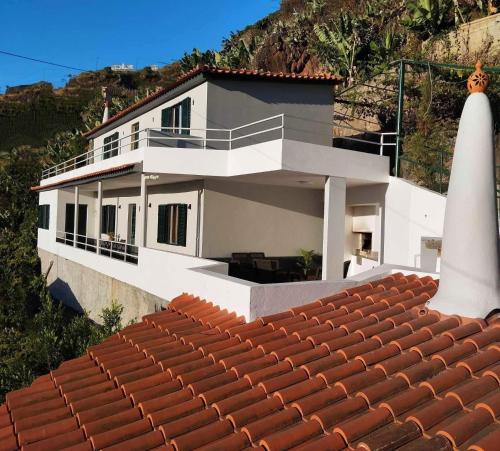 a white house with a red tile roof at Quinta do Araújo - GuestHouses in Câmara de Lobos