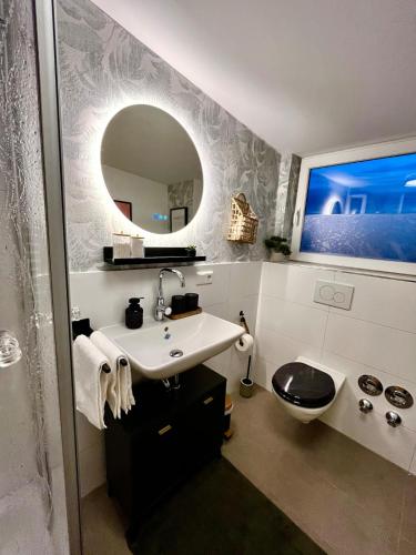 a bathroom with a sink and a toilet and a mirror at 2-Zimmer Apartment - Zentral über den Dächern von Aschaffenburg - 5 min vom HBF - Gegenüber City Galerie in Aschaffenburg