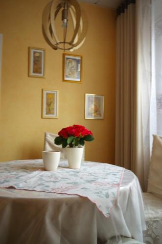 a table with a vase with red flowers on it at City Apartment Papenburg in Papenburg