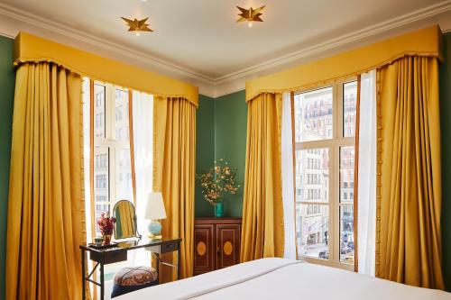 a bedroom with yellow curtains and a bed and a window at The Fifth Avenue Hotel in New York