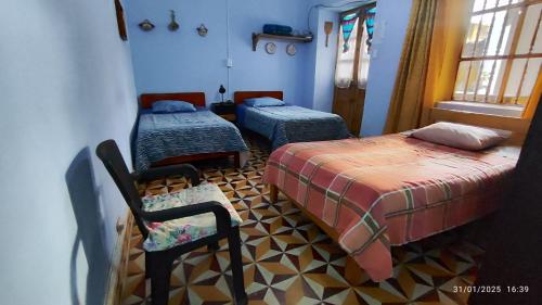 ein Zimmer mit 2 Betten und einem Stuhl darin in der Unterkunft Casa El Capulí in Cajamarca