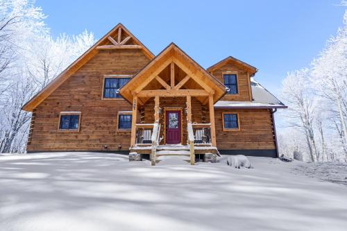 a log home in the snow with a dog in front at Shawnee Ridge Lodge in Banner Elk