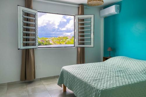 een slaapkamer met een bed en een raam met uitzicht bij Mqro11 4 et 1 in Le Robert