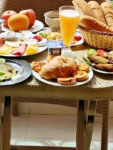 een tafel met borden en een glas sinaasappelsap bij Pyramids Heritage suites in Ghaţāţī