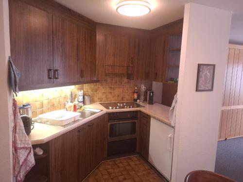 a kitchen with wooden cabinets and a stove top oven at Ski fahren-Schneeschuhwandern-Langlauf inkl Hallenbad in Luzein