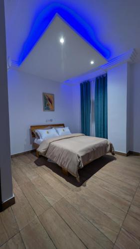 a bedroom with a large bed with a blue ceiling at Complexe Singa in Bingerville
