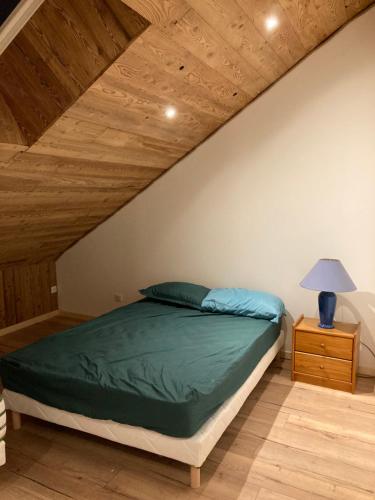 - une chambre avec un lit vert et un plafond en bois dans l'établissement Gîte La Grange, à Germéfontaine