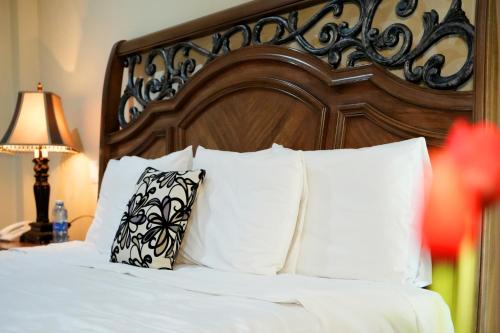 a bed with white pillows and a wooden headboard at Hotel Real de La Peña in Bernal