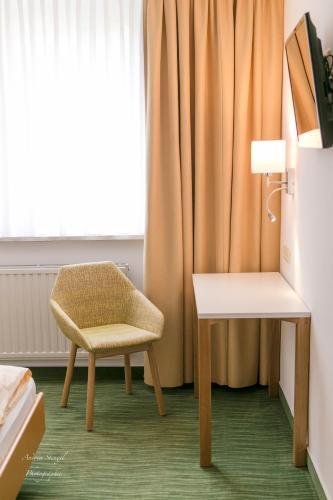 a room with a chair and a table and a window at Waldhotel Linzmühle in Kahla