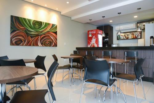 a restaurant with tables and chairs and a painting on the wall at Alano Executivo Hotel in Cachoeirinha