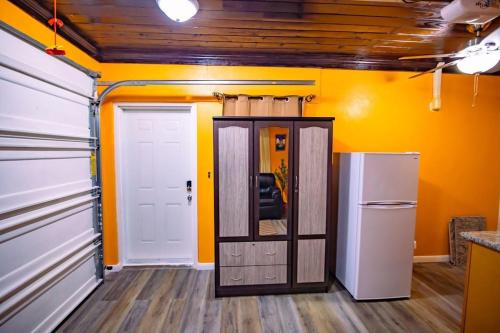 a room with a refrigerator and a kitchen with yellow walls at Tangerine Sunsets Mango in Nassau