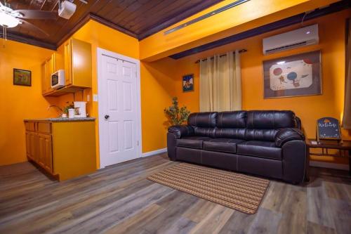 a living room with a leather couch and yellow walls at Tangerine Sunsets Mango in Nassau