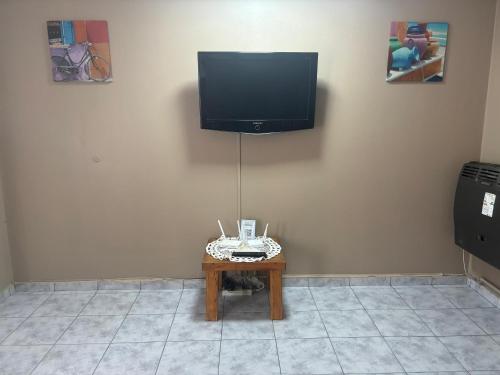 una TV a schermo piatto appesa a una parete con un tavolo di lo de fernando 2 a Río Gallegos