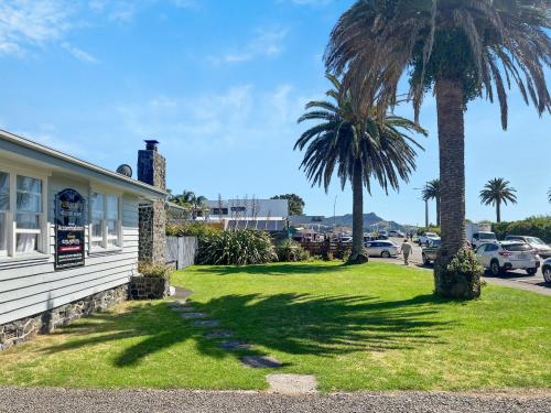 a yard with palm trees next to a building at The Publican's Palace in Whitianga