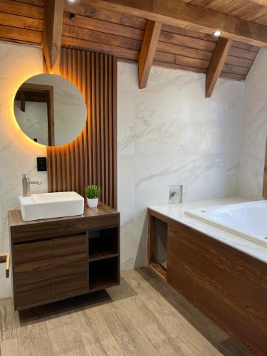 a bathroom with a sink and a tub and a mirror at Cabaña del tigre #2 in Mazamitla