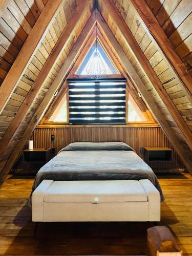 a bed in a attic with a large window at Cabaña del tigre #2 in Mazamitla