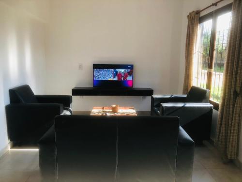 ein Wohnzimmer mit schwarzen Stühlen und einem TV in der Unterkunft Somos Río in La Cruz