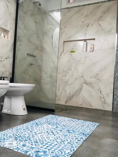 a bathroom with a shower and a blue and white rug at Somos Río in La Cruz