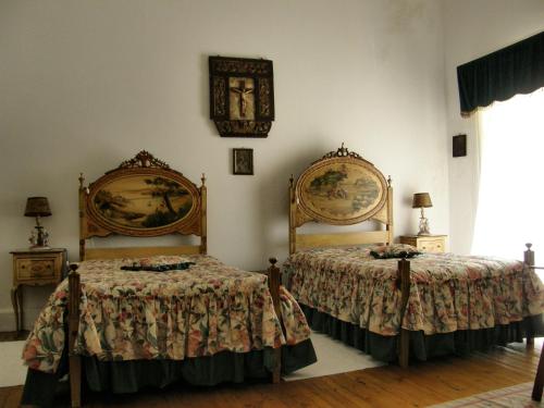 a bedroom with a bed, a desk and a painting on the wall at Solar das Avencas in Portalegre