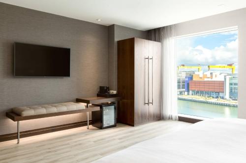 a bedroom with a television and a bed with a window at AC Hotel by Marriott Belfast in Belfast
