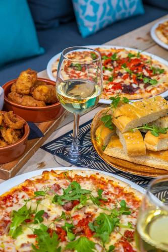 a table with several pizzas and a glass of wine at AC Hotel by Marriott Belfast in Belfast