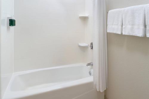 a white bath tub in a bathroom with towels at Courtyard by Marriott Perimeter Center in Atlanta