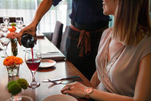 a woman sitting at a table with a man pouring a glass of wine at Twelve Downtown, Autograph Collection in Atlanta