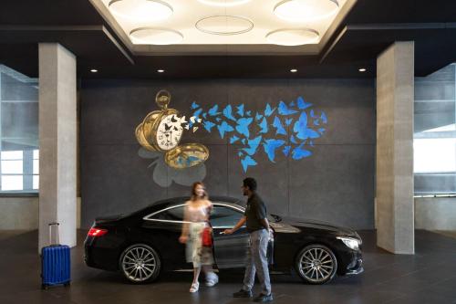 a man and a woman standing next to a black car at Twelve Downtown, Autograph Collection in Atlanta