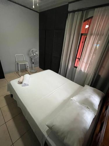 a bed in a room with a window and a chair at Villa tico House in Cariari