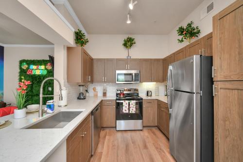 a kitchen with wooden cabinets and a stainless steel refrigerator at The Super Mario Bros Movie - 2BR-NRG-Med Center-Galleria in Houston