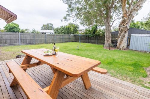 a wooden picnic table with a bottle of wine on a deck at The Beach Shack 28 Shoal Bay Road fantastic original beach house that allows pets in Shoal Bay