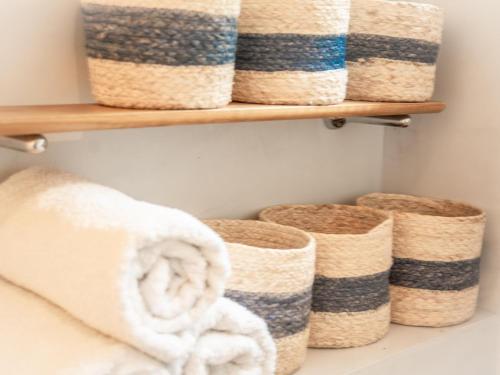 - une salle de bains pourvue de serviettes et de paniers sur une étagère dans l'établissement Maison l Arc, à Valbonne