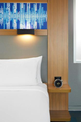 a bed with a clock on a night stand next to it at Aloft Austin at The Domain in Austin