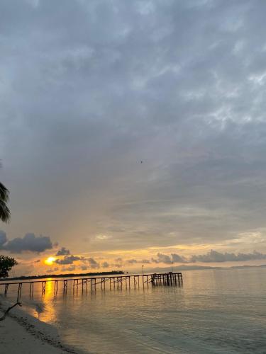 a pier on the beach with the sunset in the background at Fam Homestay in Fam