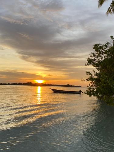 a boat sitting on the water at sunset at Fam Homestay in Fam