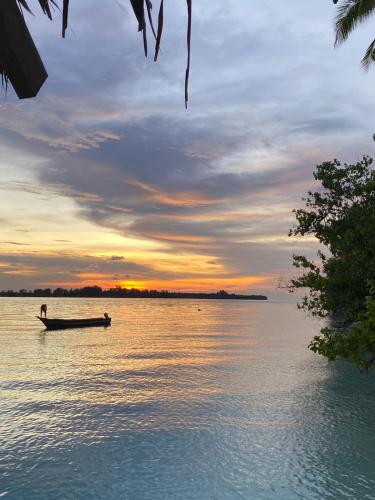 a man in a boat on the water at sunset at Fam Homestay in Fam