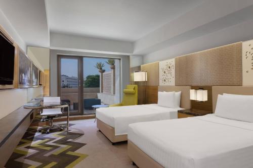 a hotel room with two beds and a desk at Courtyard by Marriott Agra in Agra