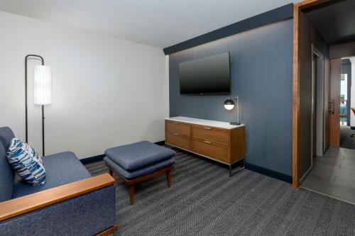 a room with a tv and a couch and a stool at Courtyard by Marriott Gainesville GA in Gainesville