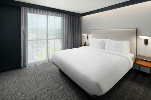 a large white bed in a hotel room with a large window at Courtyard by Marriott Gainesville GA in Gainesville