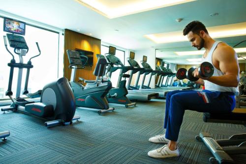 a man exercising in a gym with dumbbells at Courtyard by Marriott Agra in Agra
