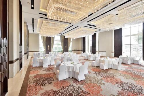 a banquet hall with white tables and white chairs at Courtyard by Marriott Agra in Agra