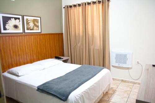 a bedroom with a bed with a blue blanket on it at Colonial Hotel Itatiba in Itatiba