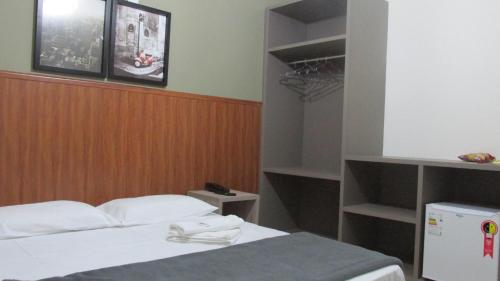 a bedroom with a bed and a closet with shelves at Colonial Hotel Itatiba in Itatiba