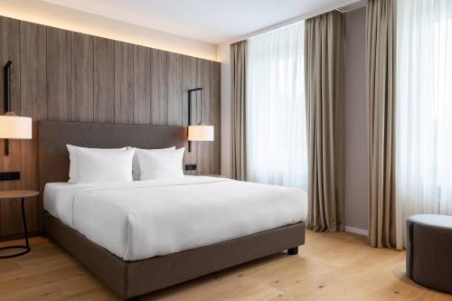 a bedroom with a large white bed and windows at AC Hotel by Marriott Berlin Humboldthain Park in Berlin