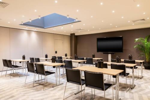 a conference room with tables and chairs and a flat screen tv at AC Hotel by Marriott Berlin Humboldthain Park in Berlin