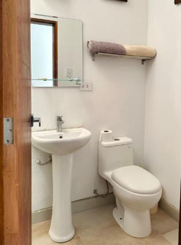 a white bathroom with a toilet and a sink at Villa MAS - Condominio Hacienda II in Pachacamac